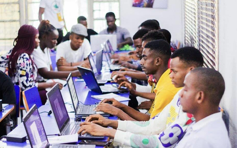 A group of Nigerian students working on laptops for freelance work.